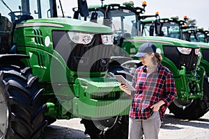 Woman farmer with a digital tablet on the background of an agricultural tractors.