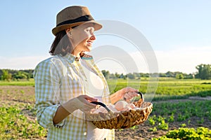 Woman farmer holding basket of fresh eggs, nature, garden, countryside background