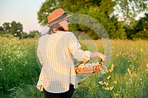 Woman farmer holding basket of fresh eggs, nature, garden, countryside background