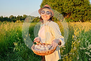 Woman farmer holding basket of fresh eggs, nature, garden, countryside background