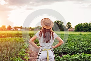 Woman farmer looking at vegetables on kitchen-garden in countryside. Agriculture and farming concept