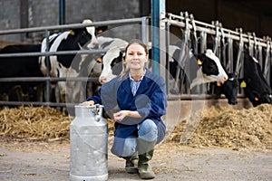 Woman farmer posing with can for milk in cowshed