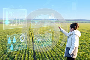 A woman farmer selects on a virtual screen the parameters that control the growth of the crop and analyzes the data using artifici photo