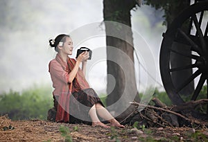 Woman farmer wearing local thai tradition sitting on her farm and buffalo  background,countryside Thailand