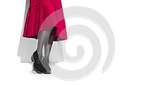 Woman fashion boots, elegant footwear. Young woman legs in suede black shoes. Red midi pleated skirt