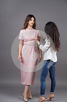 Woman fashion designer measuring dress on fashion model girl