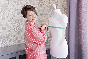 Woman fashion designer measuring tape on mannequin. Seamstress or tailor holding tape meter on dummy in home creative