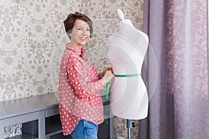 Woman fashion designer measuring tape on mannequin. Seamstress or tailor holding tape meter on dummy in home creative