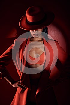 Woman, fashion hat and spotlight for suit, sexy and mystery in studio for beauty, punk aesthetic and cosmetics. Fashion