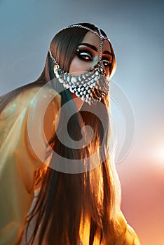 Woman in fashion latex clothes and long hair and silver face mask