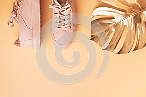 Woman fashion pink shoes and golden tropical monstera leaf on pink background with copy space. Top view. Flat lay. Fitness, sport