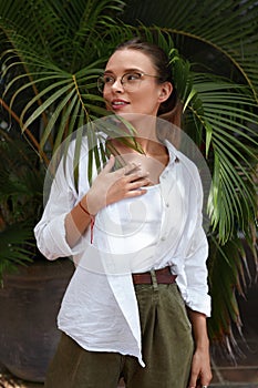 Woman. Fashion Portrait Of Beautiful Model Against Palm Leaves. Stylish Girl In Casual Clothes Standing On Tropical Greenery