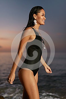 Woman Fashion. Stylish Girl In Swimsuit At Sea Coast At Sunset