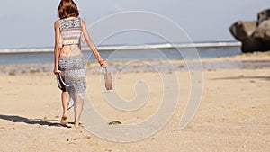 Woman with fashionable stylish nude rattan bag on the beach. Tropical island of Bali. Handmade Rattan eco handbag HD