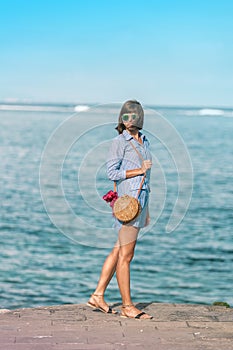 Woman with fashionable stylish rattan bag and silk scarf outside. Tropical island of Bali, Indonesia. Rattan handbag and