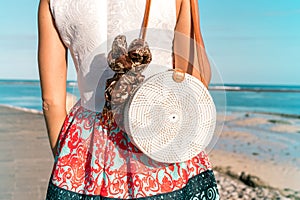 Woman with fashionable stylish rattan bag and silk scarf outside. Tropical island of Bali, Indonesia. Rattan handbag and