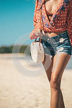 Woman with fashionable stylish rattan bag and silk scarf outside. Tropical island of Bali, Indonesia. Rattan handbag and