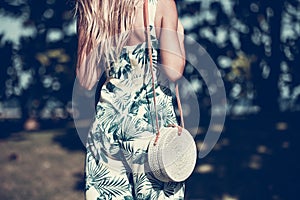 Woman with fashionable stylish rattan bag and silk scarf outside. Tropical island of Bali, Indonesia. Rattan handbag and