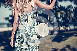 Woman with fashionable stylish rattan bag and silk scarf outside. Tropical island of Bali, Indonesia. Rattan handbag and