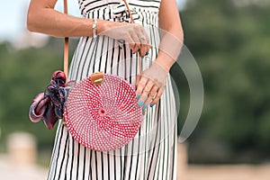 Woman with fashionable stylish red rattan bag and silk scarf outside. Tropical island of Bali, Indonesia. Rattan handbag