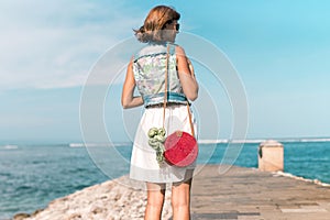 Woman with fashionable stylish red rattan bag and silk scarf outside. Tropical island of Bali, Indonesia. Rattan handbag