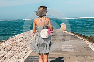 Woman with fashionable stylish white rattan bag and silk scarf outside. Tropical island of Bali, Indonesia. Rattan