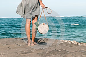 Woman with fashionable stylish white rattan bag and silk scarf outside. Tropical island of Bali, Indonesia. Rattan