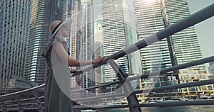 Woman in fashionable summer dress and hat enjoying Dubai city architecture in United Arab Emirates