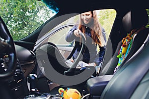 Woman fastening her son on a baby seat in a car.