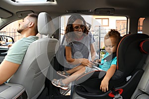 Woman fastening her son with car safety belt