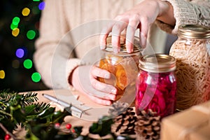 Woman Fastening Lids On Homemade Jars Of Preserved Fruit For Eco Friendly Christmas Gift photo