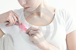 Woman fastening a pink ribbon