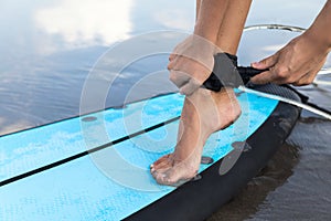 Woman is fastening surfing leash on her ankle