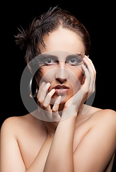 Woman with feather and goth make up on black background