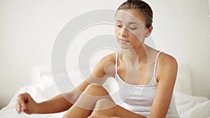 Woman with feather touching bare legs on bed