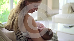 Woman feeding baby and sitting on couch in apartment room indoors spbd.