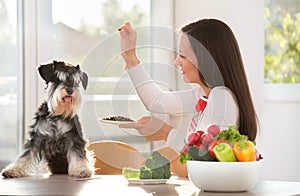 Woman feeding dog at kitchen table