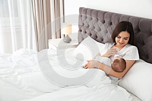 Woman feeding her baby from bottle on bed.