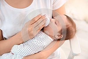 Woman feeding her baby from bottle at home
