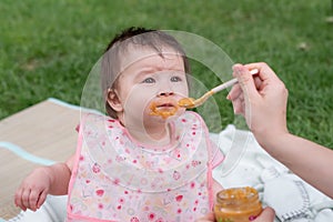 woman feeding her beautiful little daughter - mother hand and close up portrait of adorable and happy baby girl eating baby