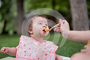 woman feeding her beautiful little daughter - mother hand and close up portrait of adorable and happy baby girl eating baby