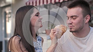 A woman is feeding her boyfriend a croissant at cafe