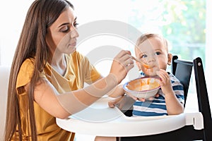 Woman feeding her child in highchair indoors