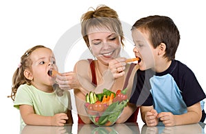 Woman feeding kids with vegetables