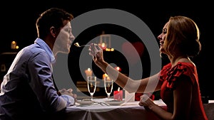 Woman feeding man during romantic evening on Valentines day, togetherness