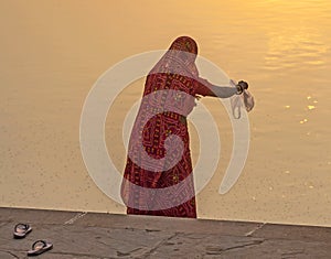 Woman feeds the fishes in the holy lake in Pushkar