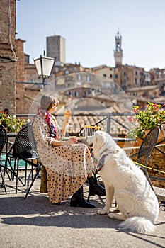 Woman feeds her dog while sitting at restaurant in SIena, Italy