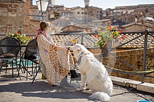 Woman feeds her dog while sitting at restaurant in SIena, Italy