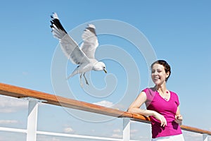 Woman feeds seagulls with bread on deck of ship.