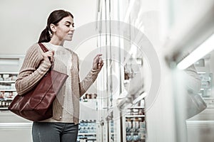 Woman feeling curious while choosing some cosmetics in pharmacy store